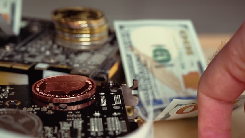 Close up cinematic footage of a hand placing a silver bitcoin on a circuit board next to other cryptocurrencies and cash