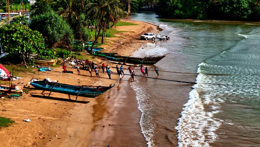 Aerial view of Galle beach with small boats resting on the sandy shoreline and gentle waves rolling onto the shore.