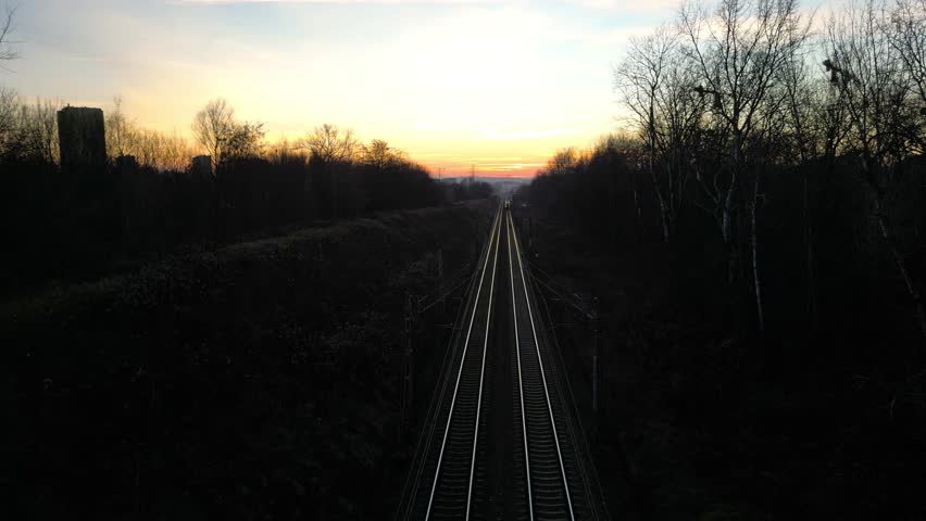High-speed train travels along railway tracks during stunning sunset, showcasing vibrant colors and dynamic movement. Passenger transportation at modern railroad. Concept of tourism trip and journey