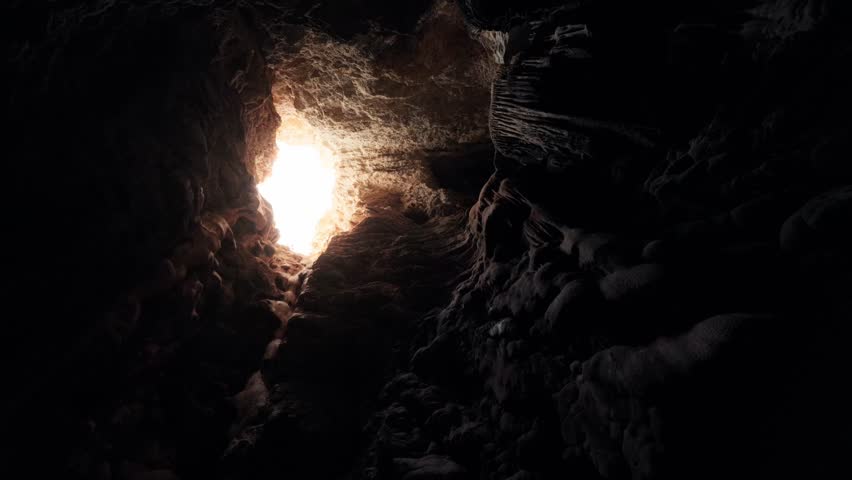 Rotating shot inside Ibiza cave looking up at sunlight entering through rocky opening.