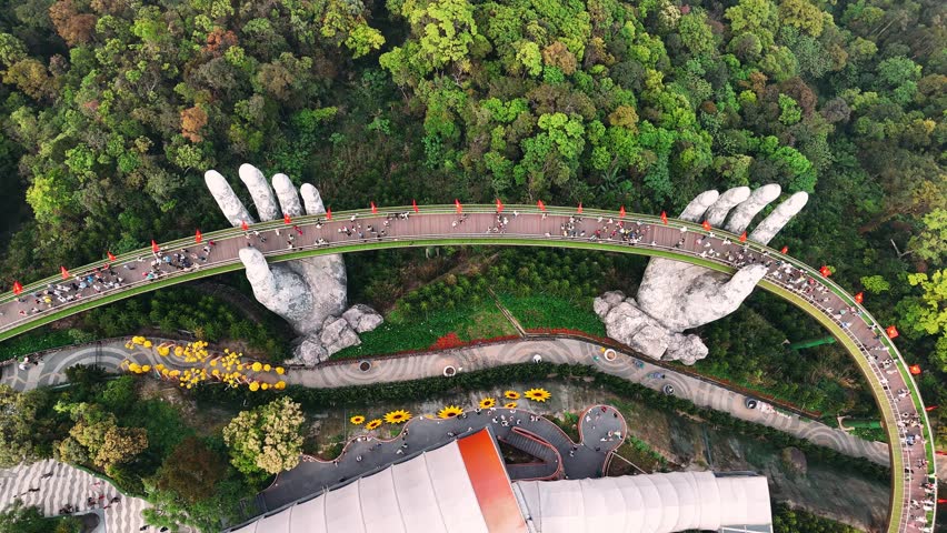 Aerial view of the famous golden bridge in ba na hills, vietnam. Tourists walking on the iconic pedestrian bridge supported by giant stone hands.
