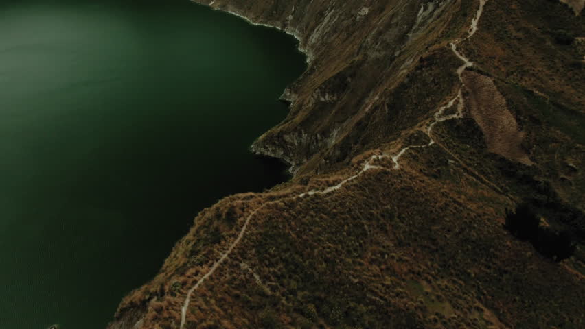 This clip showcases an aerial perspective of a tranquil lake bordered by steep, rocky hills, highlighting the natural beauty of the landscape.
