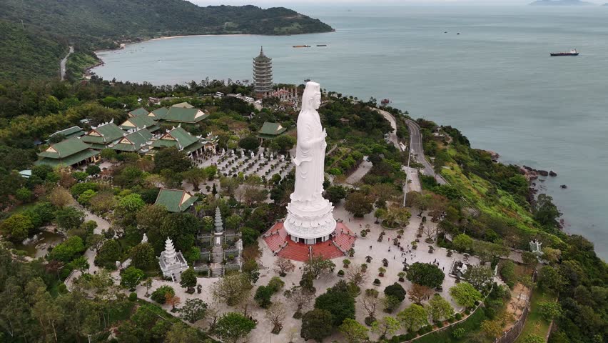 Aerial view of the lady buddha statue at linh ung pagoda in da nang, vietnam with scenic ocean and mountain landscape.