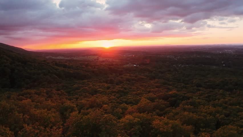 Red Sun Sets Behind Lush Hills At Dusk. Aerial Perspective Of Twilight Illuminating Forested Landscape. Vivid Sunset Casting Warm Colors Over Tennessee Hills With Tranquil Scenery