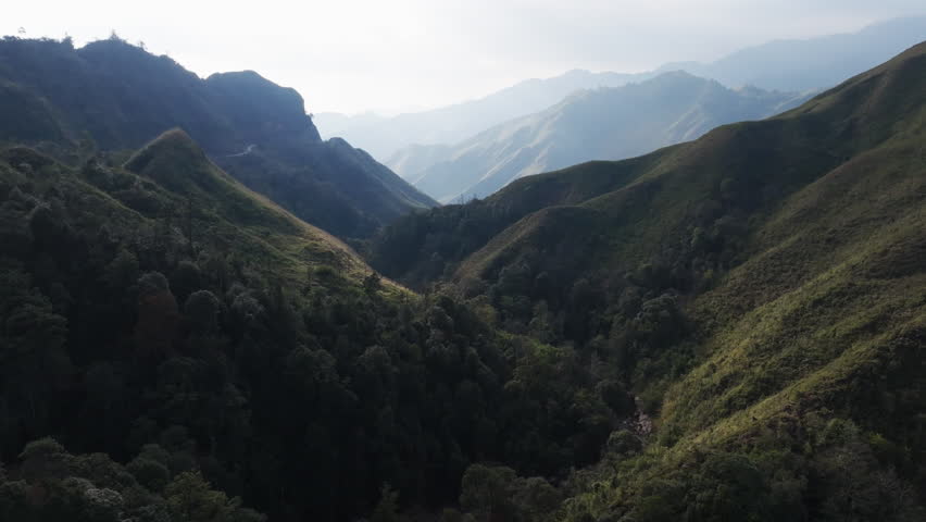 Gliding aerial footage presents a wide scenic ridge of rice terraces with layered mountains beyond at sunrise in Mui Giay, Mu Cang Chai district, Yen Bai province, Vietnam.