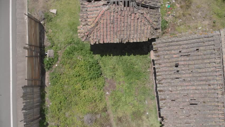 Wide view of an abandoned house in ambato near a road over a green grass terrain