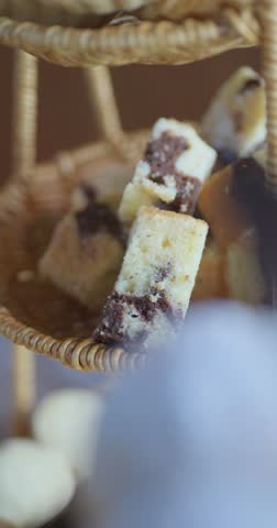 A basket of assorted baked goods, including a chocolate chip cookie. The basket is filled with a variety of treats, including a few cakes and a few cookies. Concept of abundance and indulgence