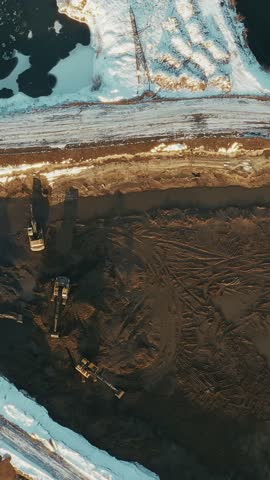 Aerial top-down view of heavy equipment excavating earth at a construction site in winter