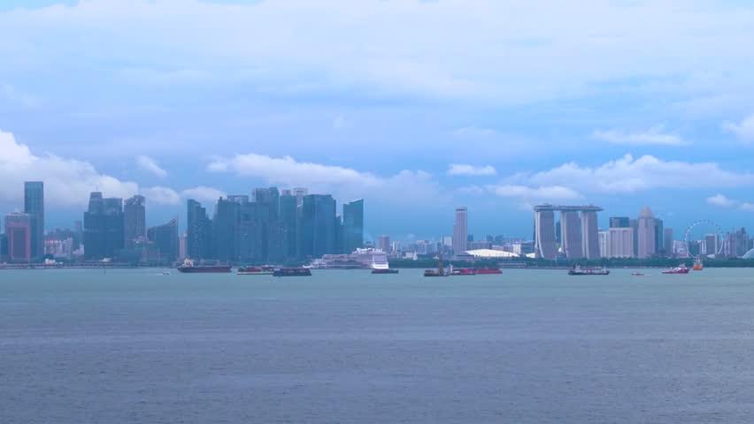 Wide Angle Panning Shot Of Singapore City Skyline At Dusk As Seen From A Ship Docked In The Harbour.