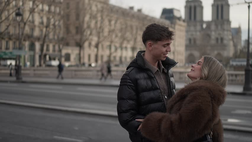 A romantic couple embraces in Paris France with the Notre Dame Cathedral visible in the background The scene captures a moment of love and affection in the iconic city.