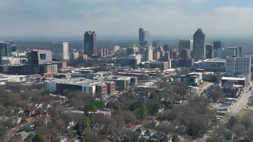 Downtown Raleigh skyline with surrounding residential neighborhoods under clear blue sky.