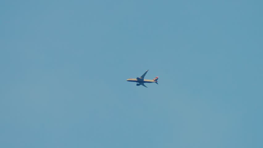 Airplane flying through evening sky at sunset light. Large cargo aircraft moving across horizon with blinking navigation lights. Heavy postal jet traveling long distance route during twilight hours