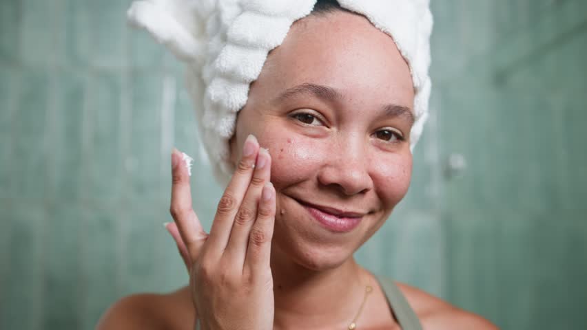 Happy Black Woman With Natural Hair Applying Moisturizer During Morning Skincare Routine