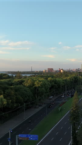 Vertical ascent reveals Parque Marinha, Guaiba Lake and Porto Alegre skyline with Usina do Gasometro tower at sunset.