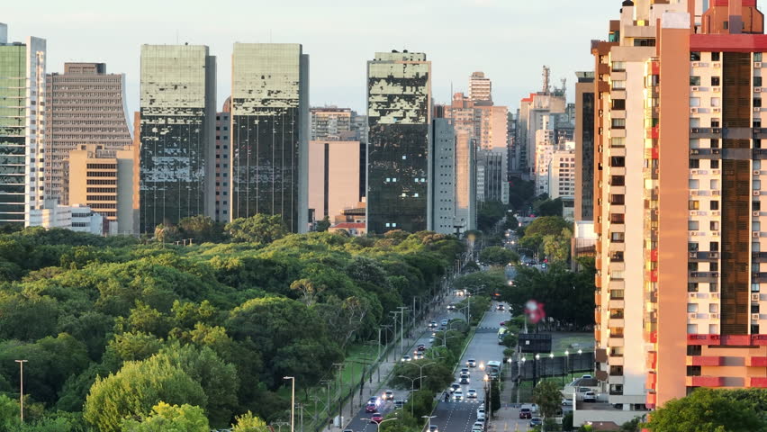 Telephoto parallax reveals Porto Alegre skyline above Parque Marinha and Borges de Medeiros Avenue traffic at sunset, 4K50.