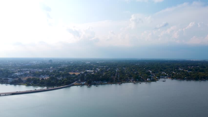 Hampton, Virginia, aerial video of the coastline, residential waterfront properties, and a long causeway bridge over the calm waters of the Chesapeake Bay area.