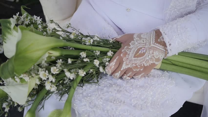 Traditional Southeast Asian white wedding dresses complete with flower bouquet decorations and ornaments, and are worn by the bride and groom. Real time outdoor natural lighting RAW no edit footage video file