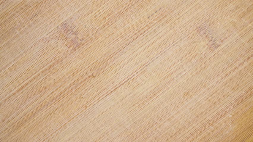 Rotating bamboo cutting board texture background. Smooth kitchen surface spinning slowly with visible knife marks and natural grain pattern