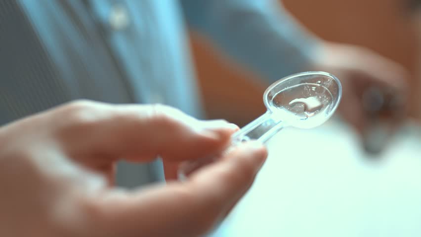 Man pouring liquid cough syrup into a spoon, medication dosage and healthcare concept.