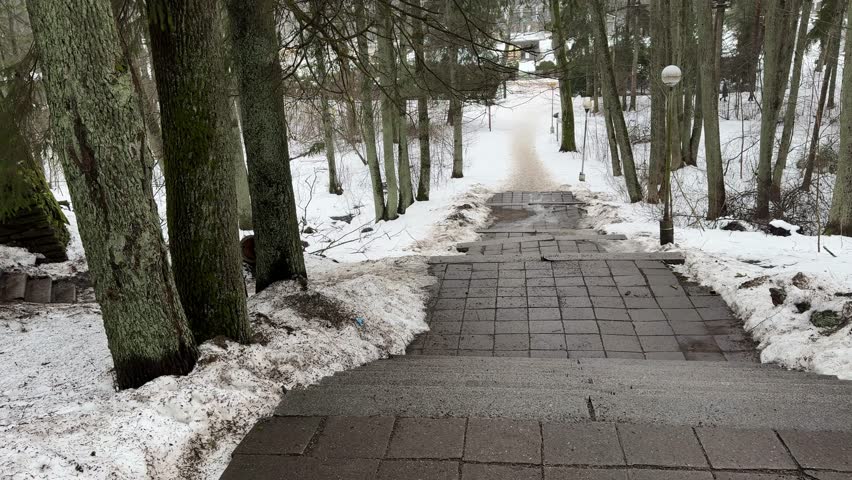 Snow-covered staircase in a winter park captured in 4K resolution. Stone steps covered with fresh snow, surrounded by frosted trees and a calm atmosphere of a cold winter day. Cinematic urban landscape, concept of silence, solitude and seasonal change. Ultra HD, high detail.