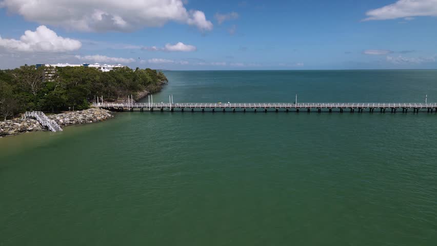 Aerial view of the waterfront esplanade and historic jetty located in the coastal town Hervey Bay Queensland Australia. Moving drone view