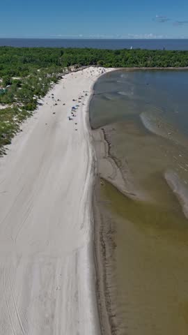 Aerial drone timelapse from far over Lake Winnipeg looking east at Grand Beach, Manitoba. Summer day with people on the beach, sandy shoreline, lagoon, and boreal forest in the background.