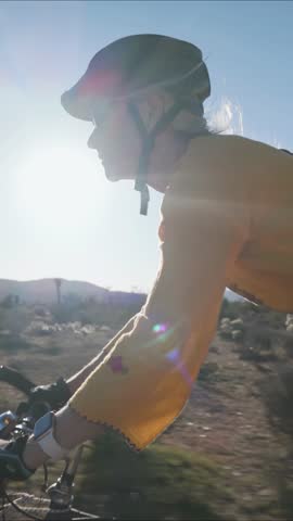 Vertical video of mature woman riding her bike through desert dirt roads in Joshua Tree National Park, enjoying the sun and beautiful landscape