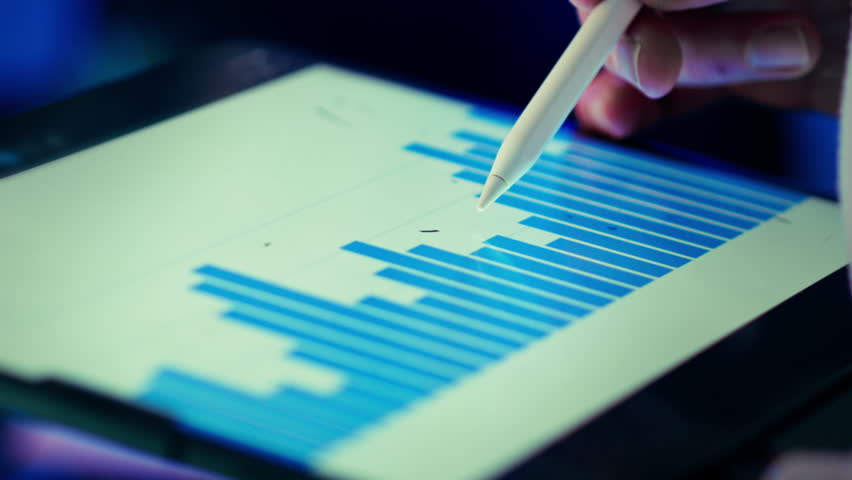 Bar chart data visualization tablet stylus closeup. Designer hand marking upward arrow digital screen horizontal bars soft focus background cool blue lighting modern studio workspace