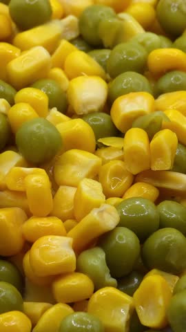 Fresh sweet corn kernels mixed with green peas macro background, vertical video