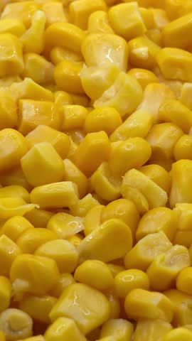 Sweet canned golden corn kernels texture background macro close up, vertical video