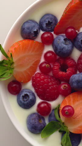 motion of raspberries falling into yoghurt cream.with movement and rotation