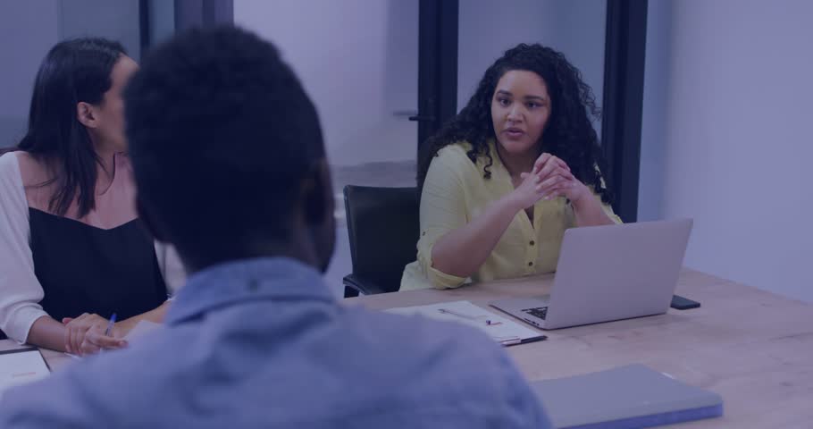 Woman in yellow starting business meeting, showing data with laptop, while binary overlay obscuring. Conference, boardroom, collaboration, teamwork, presentation, gesture, office