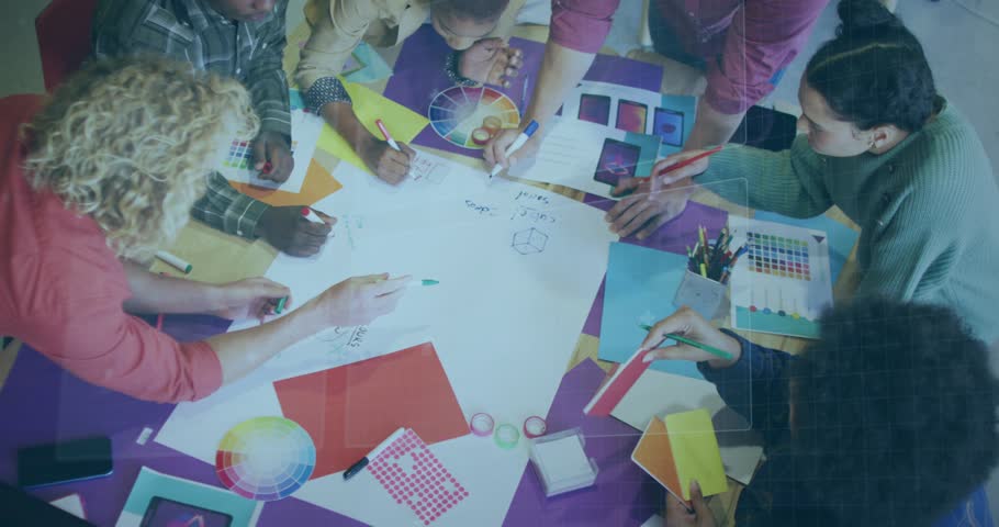 Design team leaning in sketching on big sheet after color wheel cue tracing circle refining palette. Collaboration, brainstorming, workshop, studio, classroom, overhead, markers