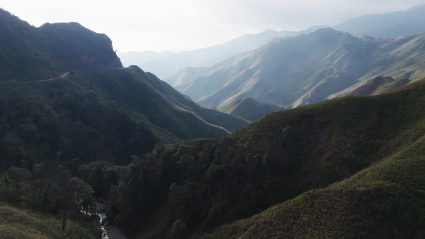 Gliding aerial footage presents a wide scenic ridge of rice terraces with layered mountains beyond at sunrise in Mui Giay, Mu Cang Chai district, Yen Bai province, Vietnam.