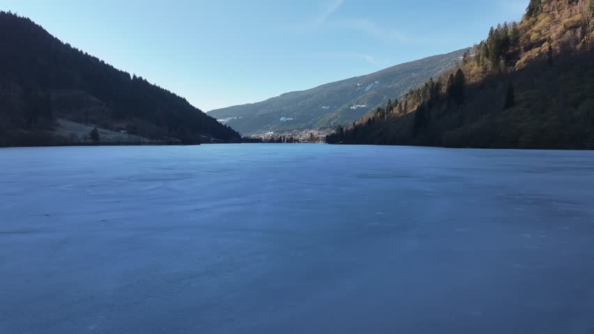 Scenic view of Afritzer See in Carinthia, Austria. Crystal clear alpine lake surrounded by rolling hills and mountain landscape under blue sky. Peaceful European summer destination.