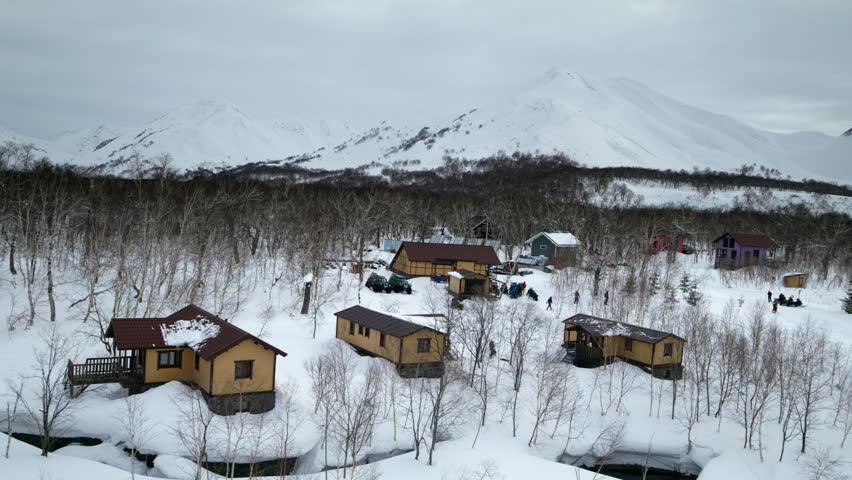Snow covered coastal homes and shoreline under overcast winter sky, aerial overview of Kamchatka Russia outpost