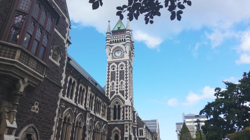 Iconic university of otago registry building, also known as the clocktower building, on a sunny day with clouds passing in dunedin, new zealand