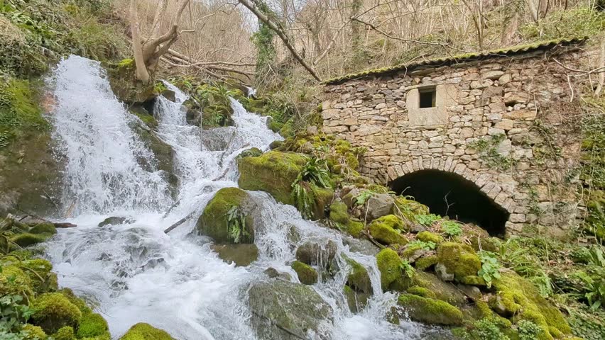 Old stone mill beside a waterfall in Belmonte de Miranda, Asturias, Spain
