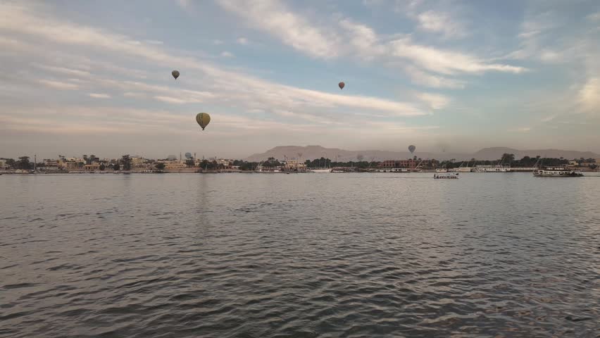 Cinematic aerial timelapse of colorful hot air balloons over Luxor Egypt at golden sunset with Nile River and ancient temples on the horizon 4K