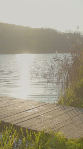 Two friends share relaxing afternoon on dockside, Casual friends walk along shoreline as sun sets quietly above