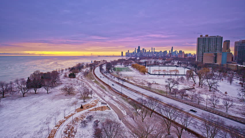 Atmospheric dawn flyover of the Chicago Loop with skyline reflections on Lake Michigan.