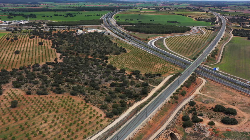 Experience a stunning aerial journey through scenic highways surrounded by vibrant fields and olive groves in the countryside, capturing nature's beauty seamlessly.