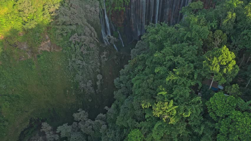 Aerial footage descending into the majestic canyon of tumpak sewu waterfall, surrounded by a lush tropical jungle in east java, indonesia