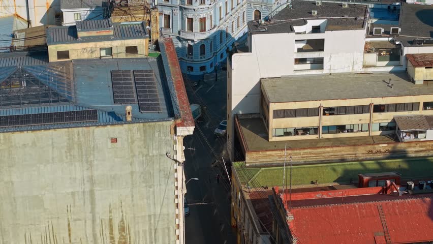 Aerial telephoto view following a trolleybus passing through the public thoroughfare with little traffic on the iconic streets of Valparaíso, Chile.