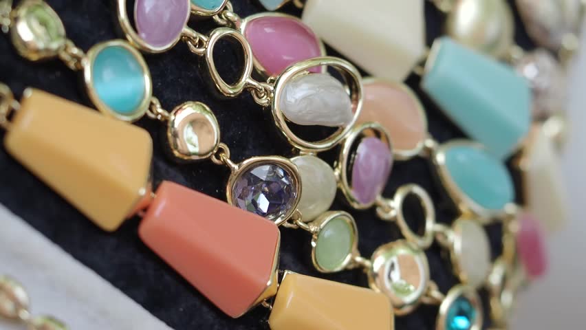 Close up of colorful necklaces with large gem stones and gold chains showcasing movement