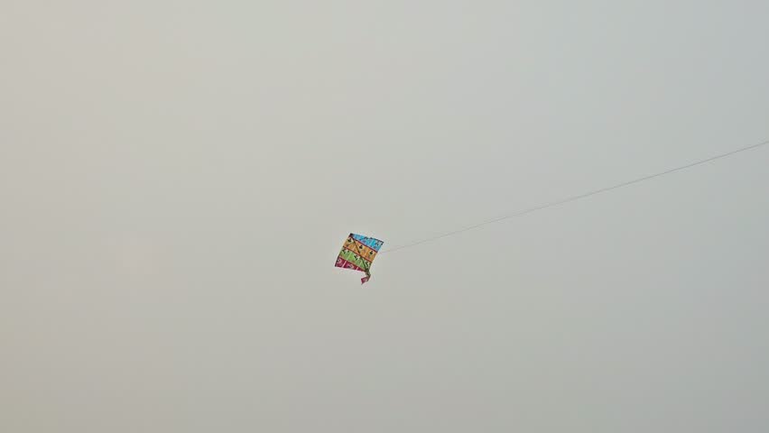 A colorful kite flying in the Blue Sky During Sunny Day . It is an Outdoor Activity.