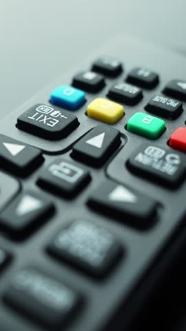 Vertical macro shot of a TV remote with a red power icon button in the foreground, shallow depth of field and soft bokeh—perfect for tech control, UI, and entertainment concepts.