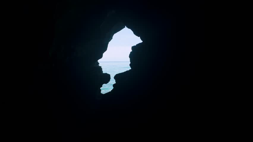 Silhouette of Africa-shaped cave opening at Caves of Hercules looking out to turquoise ocean.
