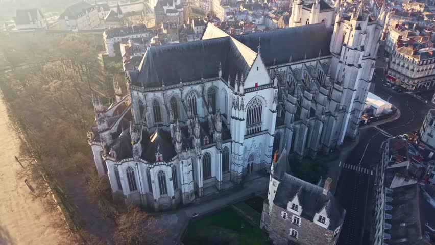 Cathedral of St Peter and St Paul and surrounding cityscape at sunrise in Nantes, France. Aerial drone tilt-up reveal