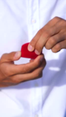 Man in a white shirt opening a red heart shaped velvet box to reveal a beautiful diamond engagement ring, a romantic gesture of love and commitment for a wedding proposal on valentine